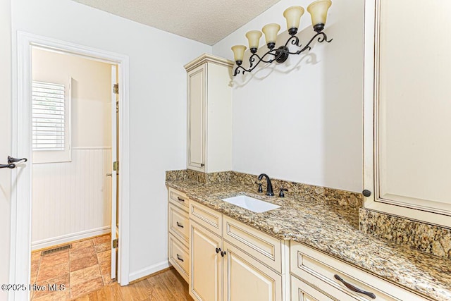 129 Shagbark Ct, Seven Lakes, NC 27376 - bathroom with vanity, wainscoting, a textured ceiling, and a chandelier