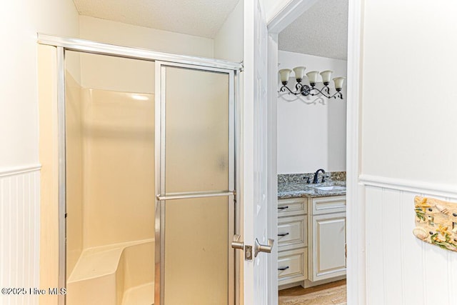 129 Shagbark Ct, Seven Lakes, NC 27376 - bathroom featuring a stall shower, wainscoting, a textured ceiling, and vanity