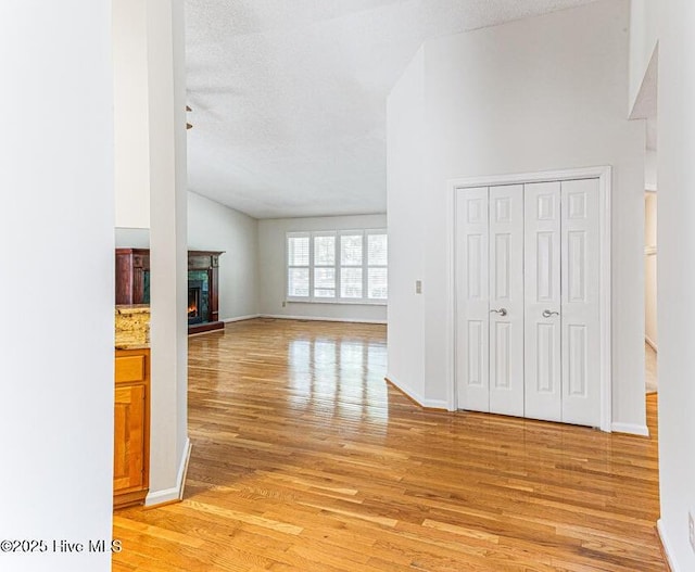129 Shagbark Ct, Seven Lakes, NC 27376 - unfurnished living room featuring light wood finished floors, vaulted ceiling, and a warm lit fireplace