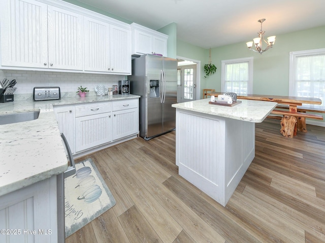106 Sound Shore Dr, Currituck, NC 27929 - kitchen featuring stainless steel refrigerator with ice dispenser, backsplash, white cabinets, a kitchen island, and light wood-style floors