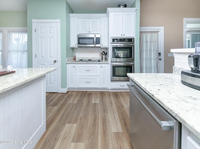 106 Sound Shore Dr, Currituck, NC 27929 - kitchen featuring stainless steel appliances, tasteful backsplash, light wood finished floors, white cabinets, and light stone countertops
