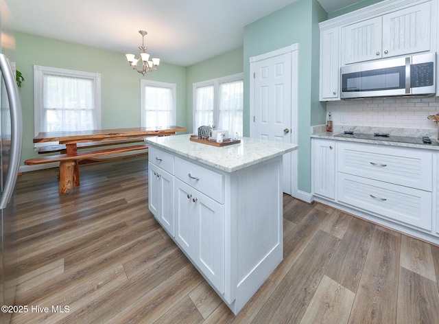 106 Sound Shore Dr, Currituck, NC 27929 - kitchen featuring stainless steel appliances, white cabinets, a chandelier, backsplash, and healthy amount of natural light