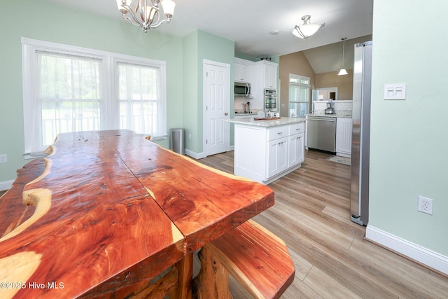 106 Sound Shore Dr, Currituck, NC 27929 - dining room with a chandelier, lofted ceiling, baseboards, and light wood-type flooring