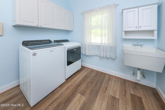 106 Sound Shore Dr, Currituck, NC 27929 - laundry area featuring separate washer and dryer, cabinet space, baseboards, and wood finished floors