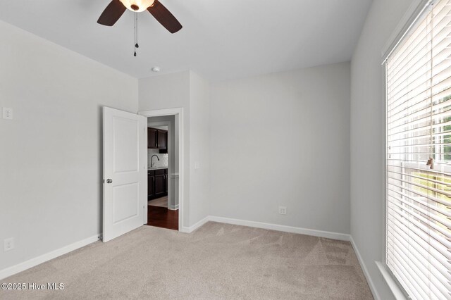 3068 Joe Stocks Rd, Greenville, NC 27858 - empty room with light colored carpet, a ceiling fan, baseboards, a sink, and a smoke detector