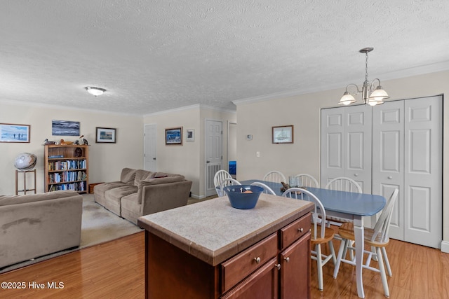 233 NE 70th St, Oak Island, NC 28465 - kitchen with light wood finished floors, ornamental molding, light countertops, pendant lighting, and a textured ceiling