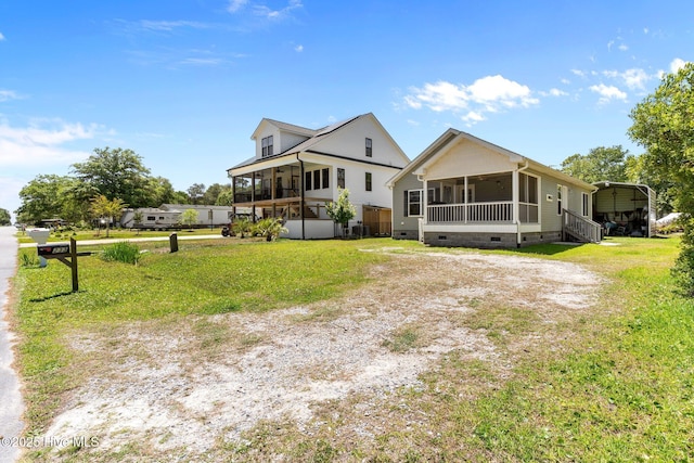 233 NE 70th St, Oak Island, NC 28465 - view of front of property with a sunroom, crawl space, driveway, a carport, and a front yard