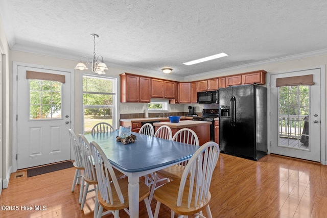 233 NE 70th St, Oak Island, NC 28465 - dining space featuring healthy amount of natural light, light wood-style floors, a chandelier, crown molding, and a textured ceiling