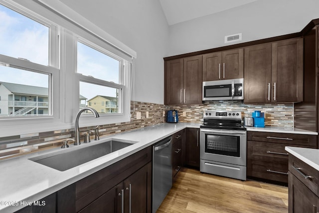 232 Seashore Dr, North Topsail Beach, NC 28460 - kitchen with stainless steel appliances, a sink, backsplash, dark brown cabinets, and high vaulted ceiling