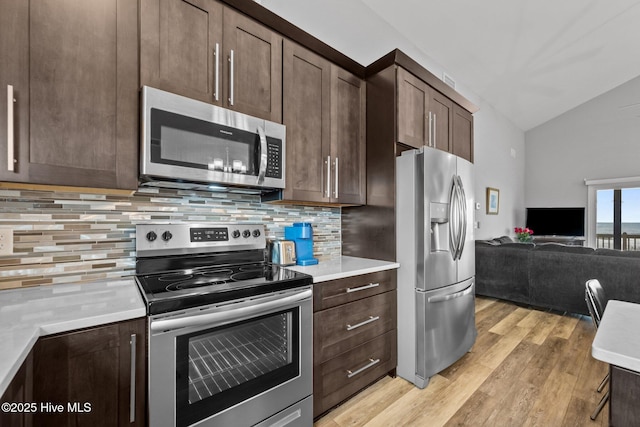 232 Seashore Dr, North Topsail Beach, NC 28460 - kitchen with stainless steel appliances, vaulted ceiling, open floor plan, dark brown cabinetry, and light wood-type flooring