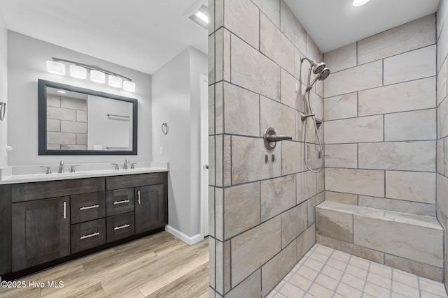 232 Seashore Dr, North Topsail Beach, NC 28460 - bathroom with a tile shower, double vanity, wood finished floors, and baseboards