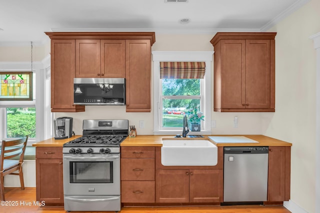 2013 Adams St, Wilmington, NC 28401 - kitchen featuring appliances with stainless steel finishes, a sink, crown molding, brown cabinets, and wood counters