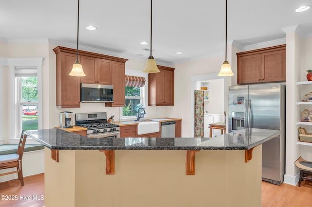 2013 Adams St, Wilmington, NC 28401 - kitchen featuring appliances with stainless steel finishes, washing machine and dryer, healthy amount of natural light, a kitchen breakfast bar, and crown molding