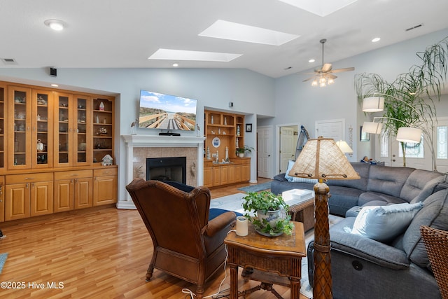 4 Golf Crest Ct, Carolina Shores, NC 28467 - living area with a tiled fireplace, light wood-type flooring, a skylight, high vaulted ceiling, and ceiling fan