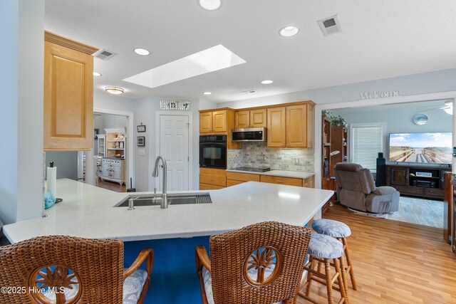 4 Golf Crest Ct, Carolina Shores, NC 28467 - kitchen featuring a sink, black appliances, a skylight, a peninsula, and a breakfast bar area