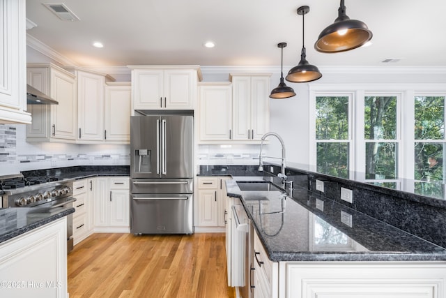 110 Dow Rd N, Carolina Beach, NC 28428 - kitchen with high end appliances, a sink, ornamental molding, light wood-style flooring, and decorative light fixtures
