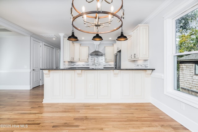 110 Dow Rd N, Carolina Beach, NC 28428 - kitchen featuring dark countertops, wall chimney exhaust hood, stainless steel fridge, light wood-style floors, and ornamental molding
