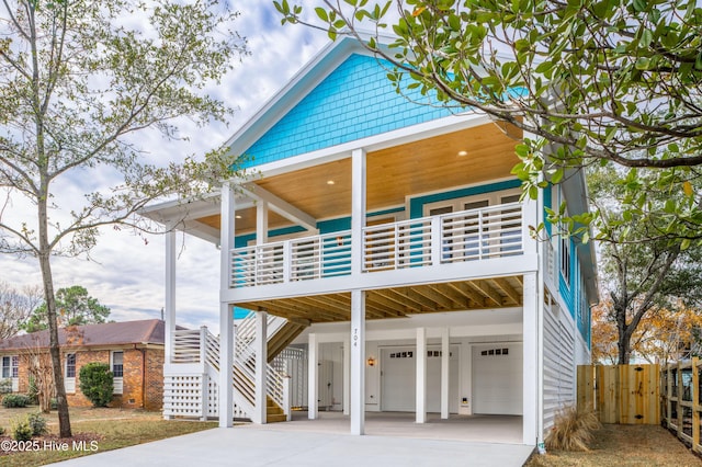 110 Dow Rd N, Carolina Beach, NC 28428 - raised beach house with driveway, stairway, a garage, a carport, and a balcony
