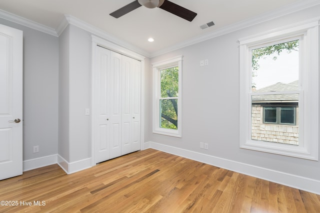 110 Dow Rd N, Carolina Beach, NC 28428 - unfurnished bedroom featuring baseboards, light wood finished floors, multiple windows, ornamental molding, and a closet