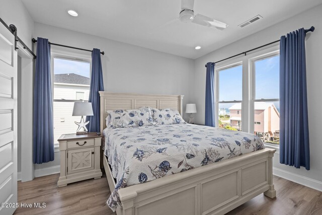1905 Emerald Dr, Emerald Isle, NC 28594 - bedroom featuring a barn door, wood finished floors, baseboards, ceiling fan, and recessed lighting