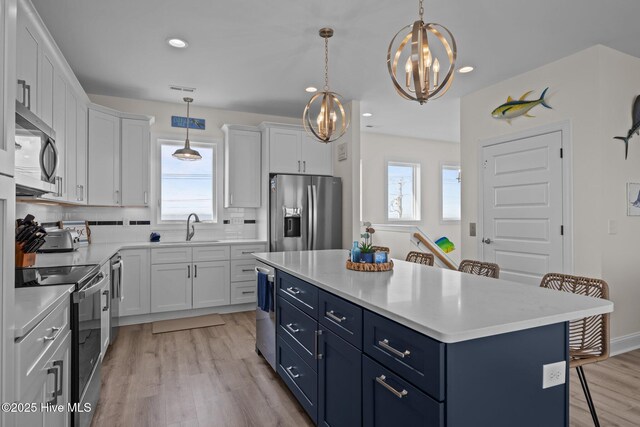 1905 Emerald Dr, Emerald Isle, NC 28594 - kitchen featuring stainless steel appliances, blue cabinets, a sink, a chandelier, and white cabinets
