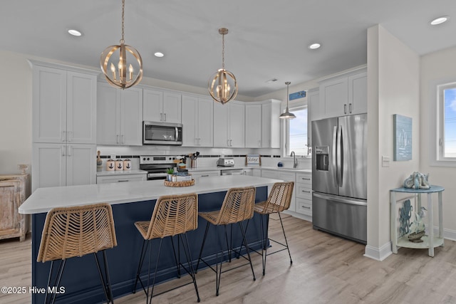 1905 Emerald Dr, Emerald Isle, NC 28594 - kitchen with stainless steel appliances, a chandelier, light countertops, a kitchen island, and light wood-style flooring