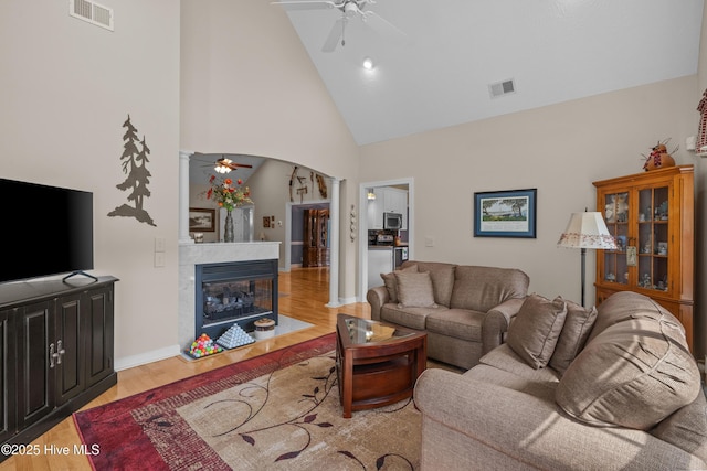550 Sunset Lakes Blvd SW, Sunset Beach, NC 28468 - living room featuring ceiling fan, wood finished floors, arched walkways, high vaulted ceiling, and a glass covered fireplace