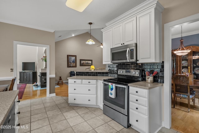 550 Sunset Lakes Blvd SW, Sunset Beach, NC 28468 - kitchen featuring appliances with stainless steel finishes, a peninsula, white cabinets, backsplash, and vaulted ceiling