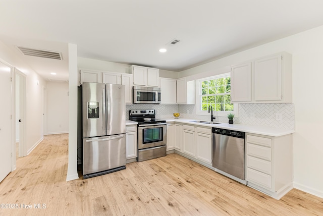 150 Willetts Dr, Southport, NC 28461 - kitchen featuring stainless steel appliances, a sink, light wood finished floors, decorative backsplash, and light countertops