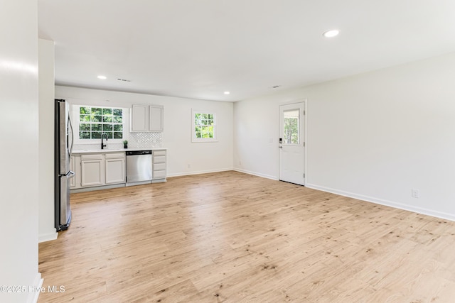 150 Willetts Dr, Southport, NC 28461 - unfurnished living room featuring light wood finished floors, recessed lighting, baseboards, and a sink