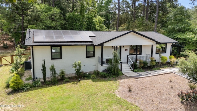 140 Timothy St, Southern Pines, NC 28387 - view of front of house with covered porch, a front yard, solar panels, central AC unit, and brick siding