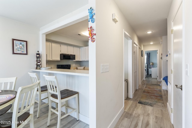 1437 Fort Fisher Blvd S Unit D3, Kure Beach, NC 28449 - kitchen with black microwave, light wood finished floors, a breakfast bar, light countertops, and baseboards