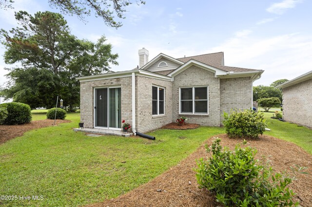 106 N Shore Dr, Sneads Ferry, NC 28460 - back of house with a chimney, brick siding, and a yard