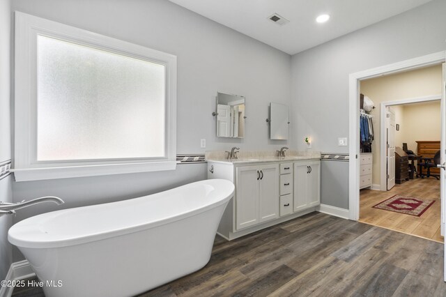 106 N Shore Dr, Sneads Ferry, NC 28460 - bathroom featuring double vanity, wood finished floors, a freestanding bath, a spacious closet, and recessed lighting