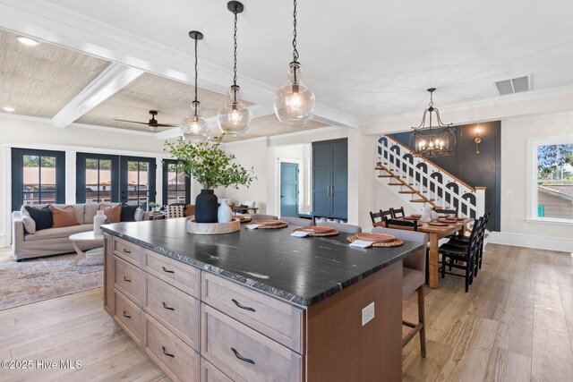 412 Keziah St, Oak Island, NC 28465 - kitchen with a kitchen bar, light wood-style floors, beam ceiling, a chandelier, and crown molding