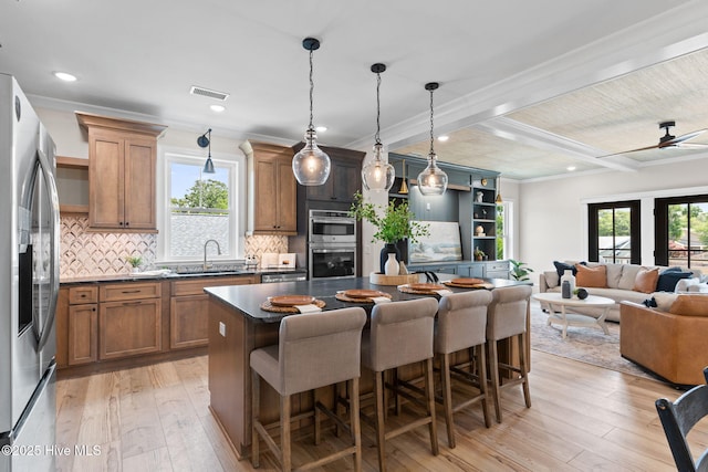 412 Keziah St, Oak Island, NC 28465 - kitchen with stainless steel appliances, dark countertops, a sink, light wood-style flooring, and a breakfast bar