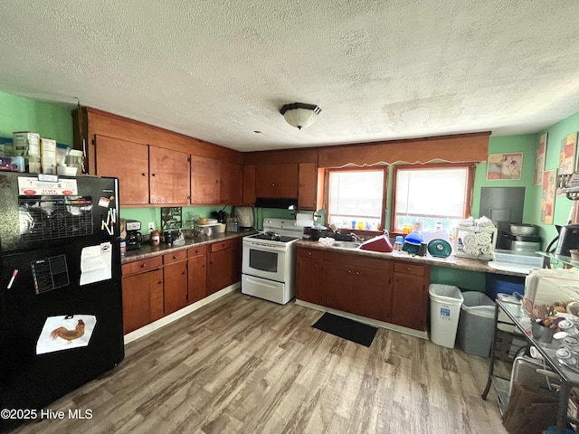 1412 Lyon Landing Rd, Elizabethtown, NC 28337 - kitchen featuring white range oven, freestanding refrigerator, a textured ceiling, light wood-style floors, and brown cabinetry