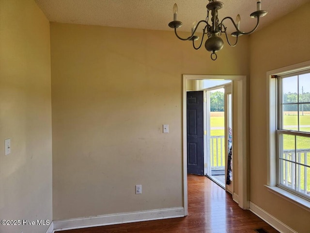 5702 Whichard Rd, Stokes, NC 27884 - spare room with a chandelier, dark wood-style floors, and baseboards