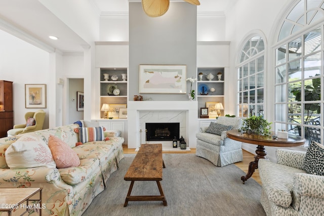 8300 Fazio Dr, Wilmington, NC 28411 - living area with ornamental molding, wood finished floors, built in shelves, a towering ceiling, and a premium fireplace