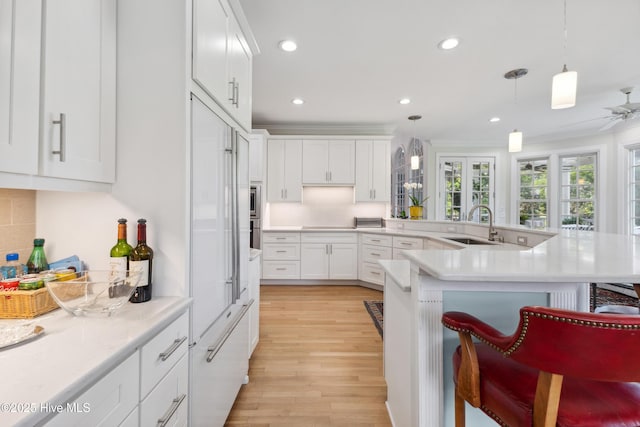 8300 Fazio Dr, Wilmington, NC 28411 - kitchen featuring a kitchen bar, recessed lighting, white cabinetry, light wood-style flooring, and light countertops