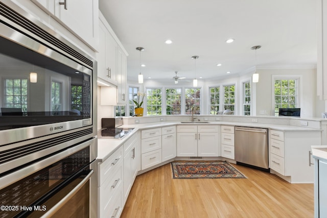 8300 Fazio Dr, Wilmington, NC 28411 - kitchen featuring appliances with stainless steel finishes, a sink, white cabinetry, light wood-style floors, and ornamental molding