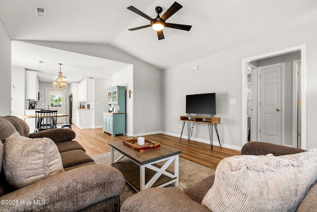 7321 Haskell Ct, Wilmington, NC 28411 - living room with light wood-type flooring, ceiling fan, a chandelier, vaulted ceiling, and baseboards