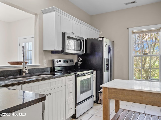 98 Mccain Ln Unit 3, Swansboro, NC 28584 - kitchen featuring stainless steel appliances, a sink, white cabinets, light tile patterned floors, and dark stone countertops