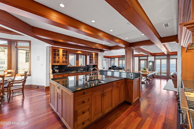 218 Row Boat Row, Bald Head Island, NC 28461 - kitchen with a sink, dark wood-style floors, baseboards, glass insert cabinets, and an island with sink