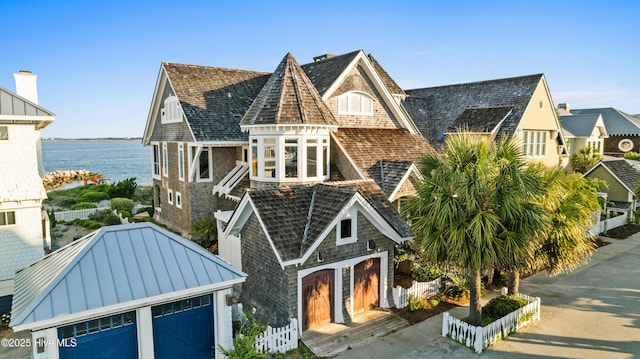 218 Row Boat Row, Bald Head Island, NC 28461 - view of front facade featuring a standing seam roof, a detached garage, metal roof, a water view, and an outbuilding