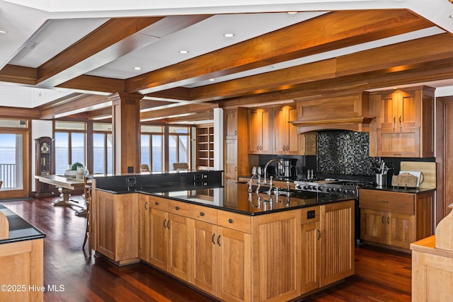 218 Row Boat Row, Bald Head Island, NC 28461 - kitchen with a sink, tasteful backsplash, dark wood-style flooring, beamed ceiling, and a kitchen island with sink