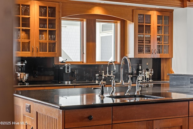 218 Row Boat Row, Bald Head Island, NC 28461 - kitchen with glass insert cabinets, a sink, tasteful backsplash, and brown cabinets