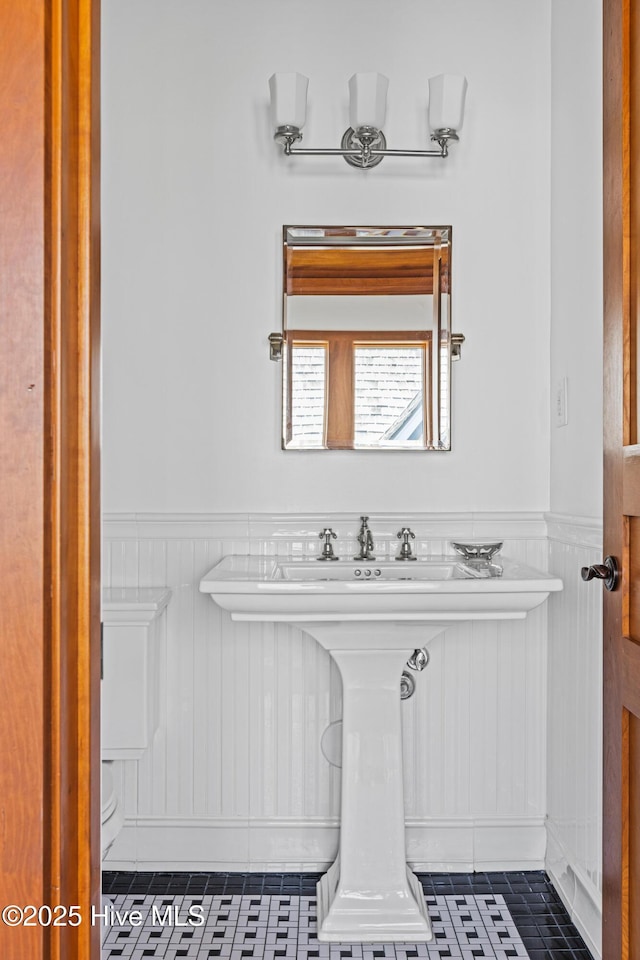 218 Row Boat Row, Bald Head Island, NC 28461 - bathroom with a wainscoted wall, tile patterned flooring, toilet, and a decorative wall