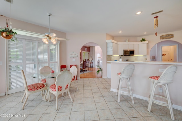 7120 Orchard Trce, Wilmington, NC 28409 - dining area with arched walkways, a ceiling fan, recessed lighting, light tile patterned floors, and baseboards