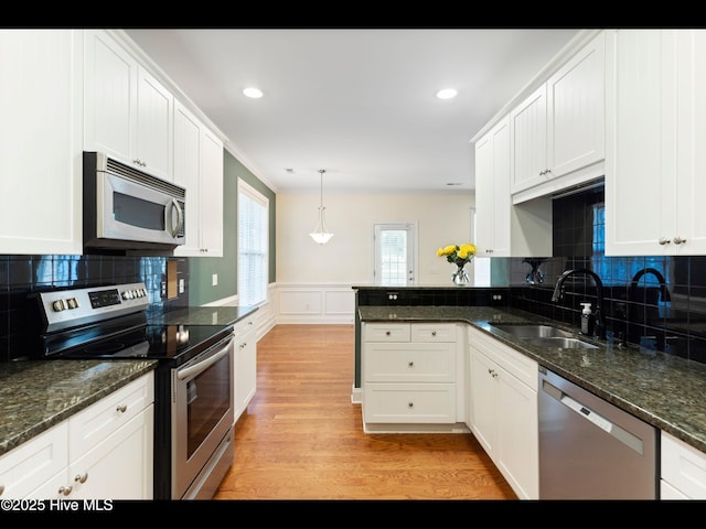 822 Lambrook Dr, Wilmington, NC 28411 - kitchen with stainless steel appliances, a sink, white cabinets, a peninsula, and light wood-style flooring